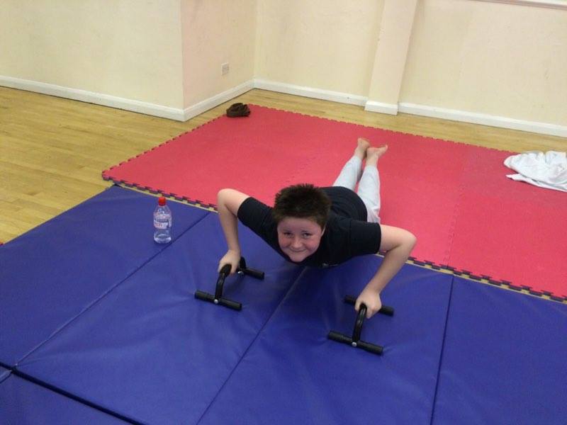A young boy is doing push ups on a mat