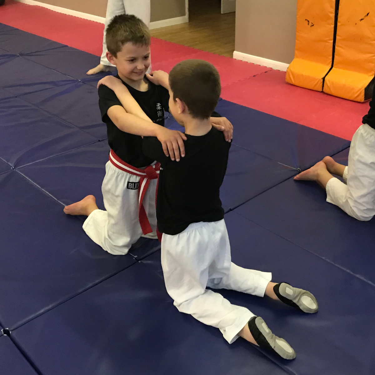 Two young boys are hugging each other on a mat