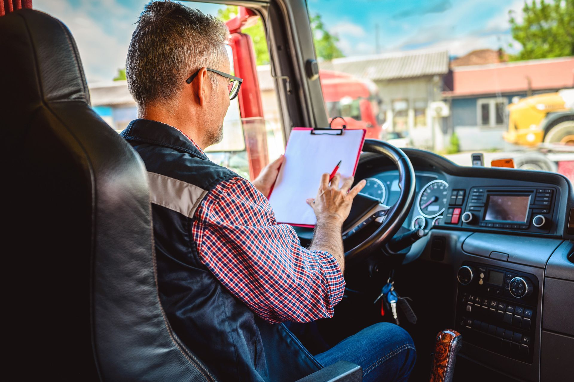 Man in truck cabin, holding clipboard, reviewing documents. Man in truck cabin, holding clipboard, reviewing documents.