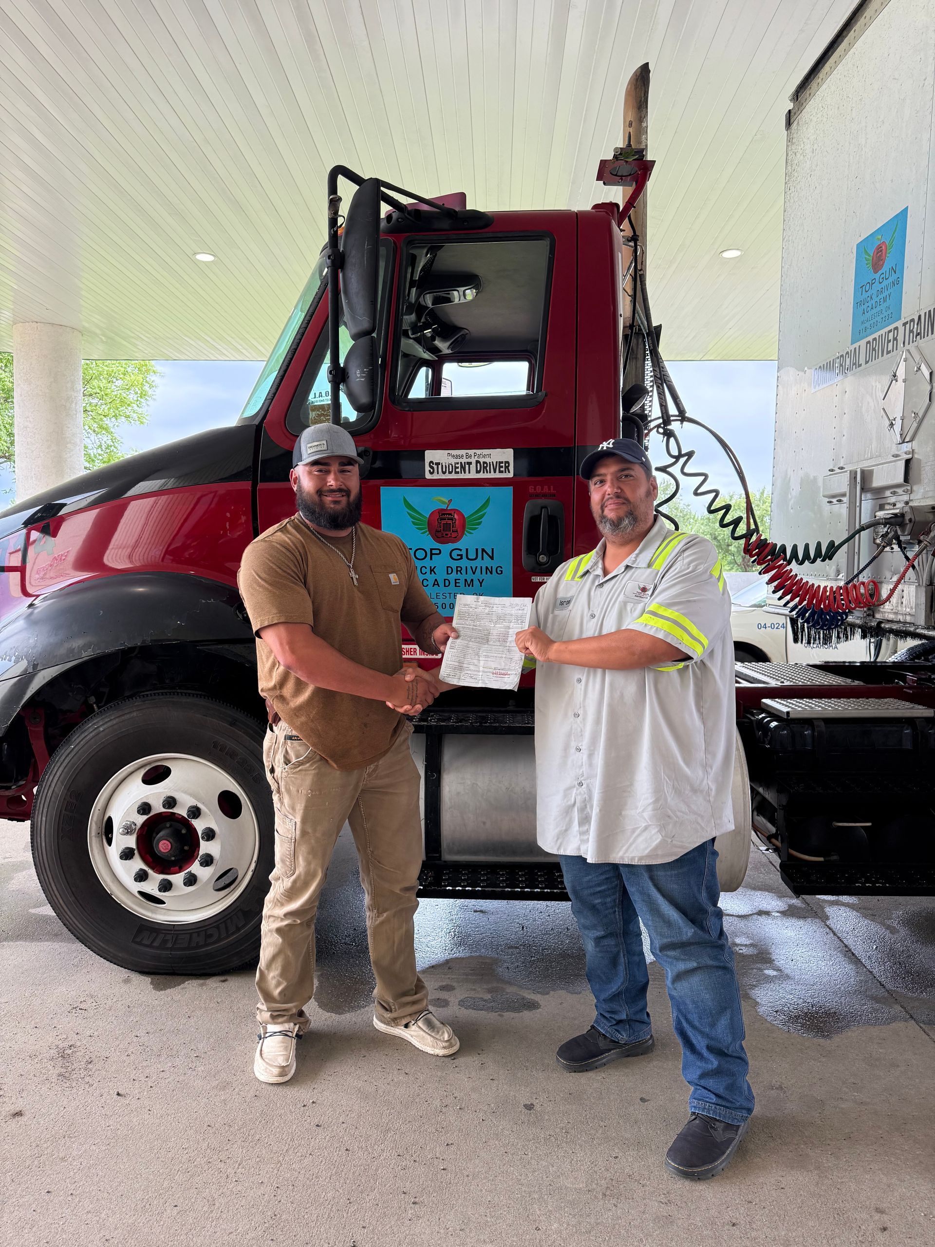 White semi-truck with red trailer, driver visible, on paved road. White semi-truck with red trailer, driver visible, on paved road.
