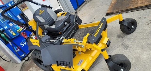 A yellow lawn mower is cutting a lush green lawn