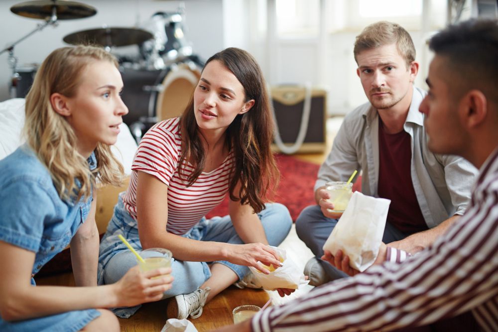 A group of people are sitting on the floor talking to each other.