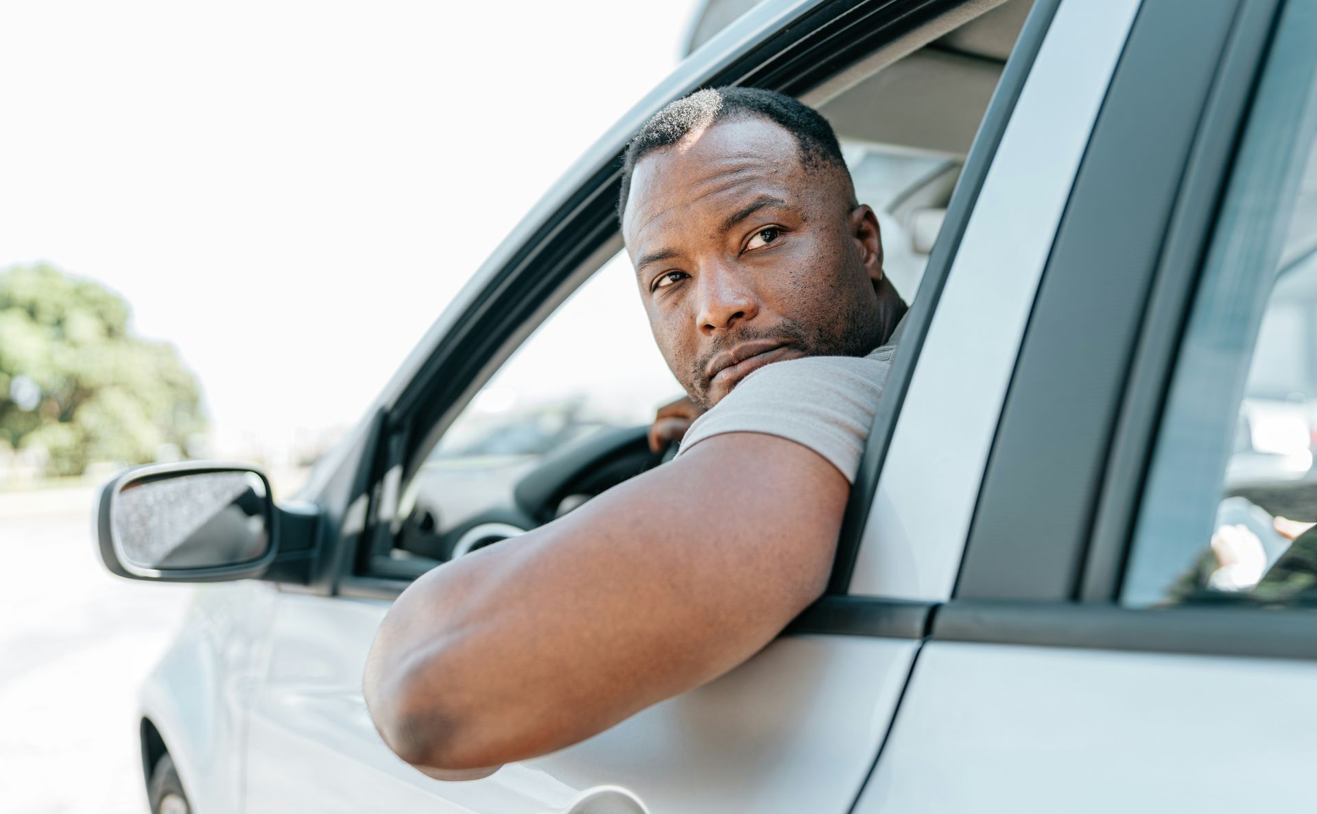 A man is leaning out of the window of a car.