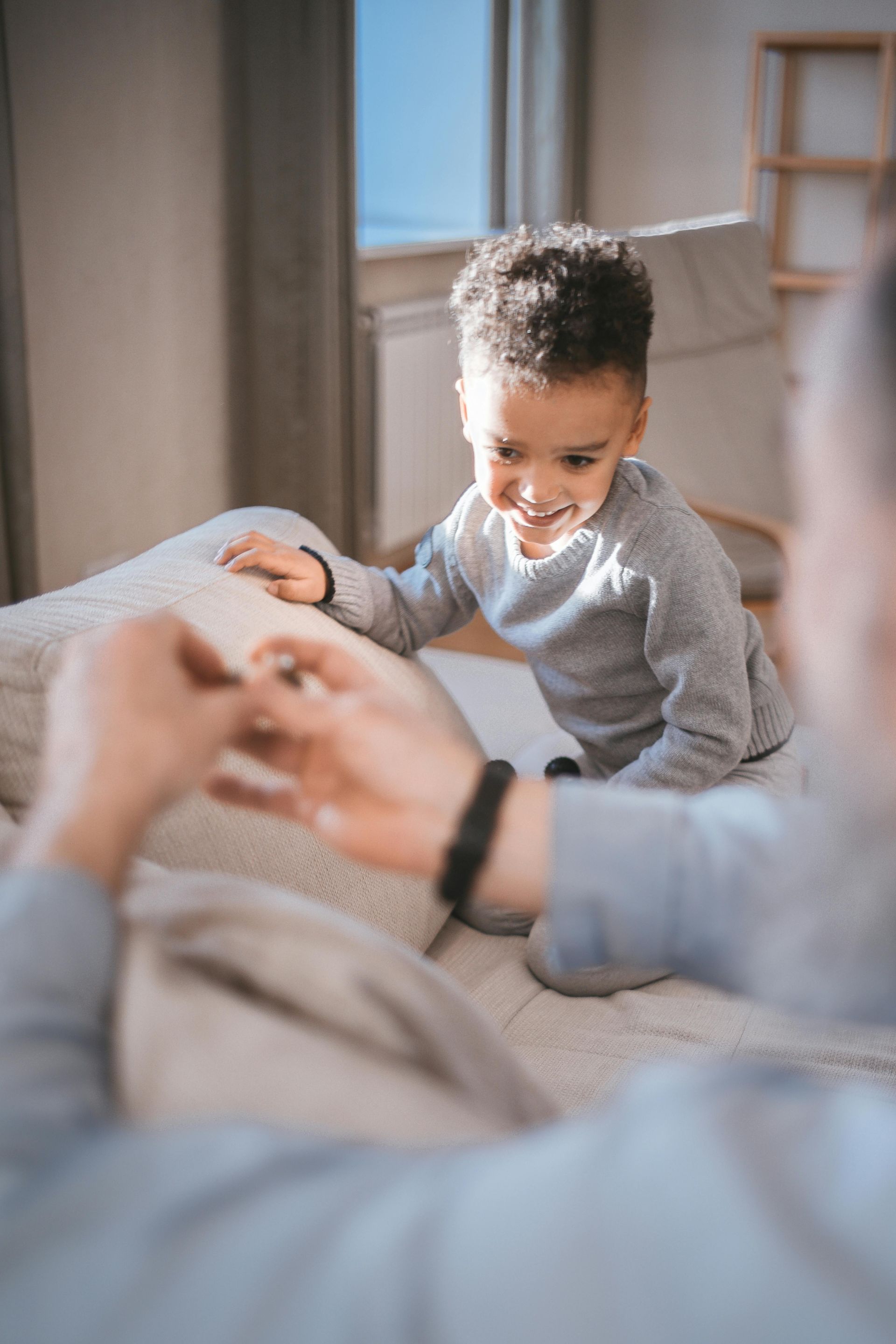 A man and a child are playing with a cell phone on a bed.