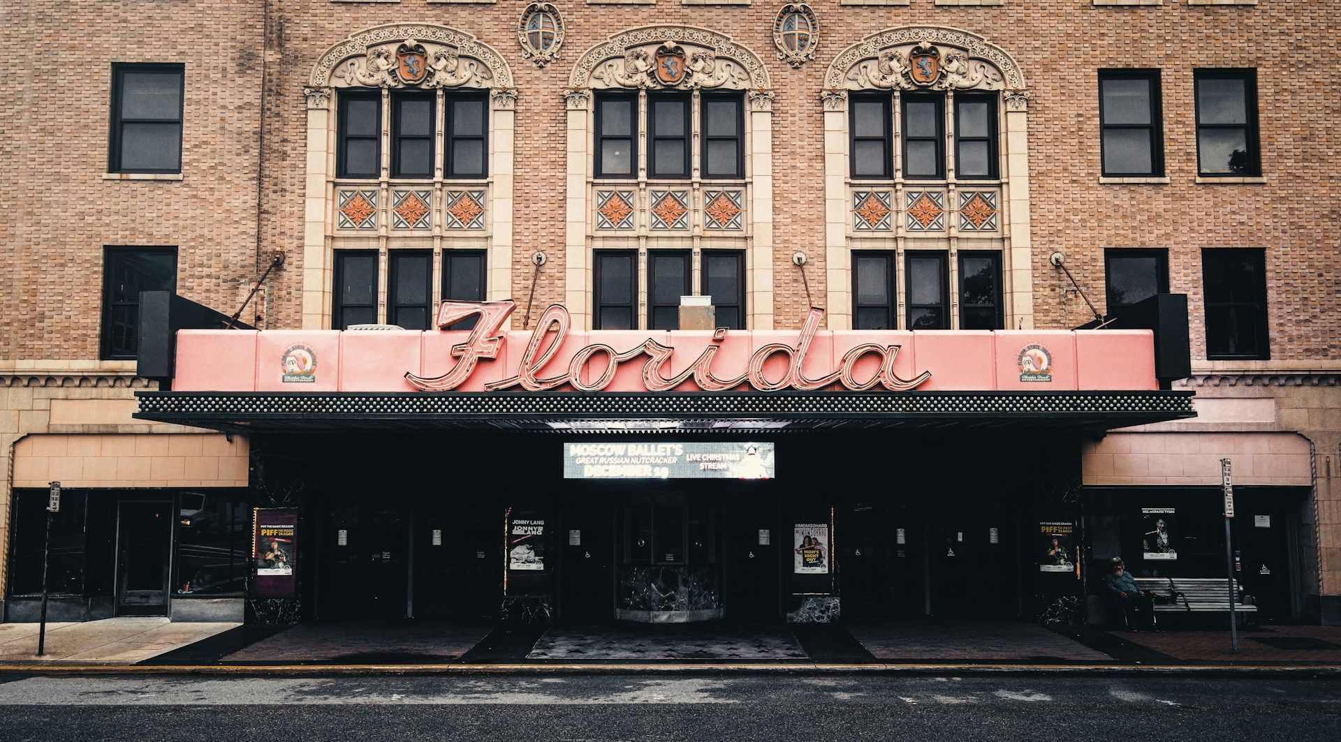 The front of a brick building with a pink awning.