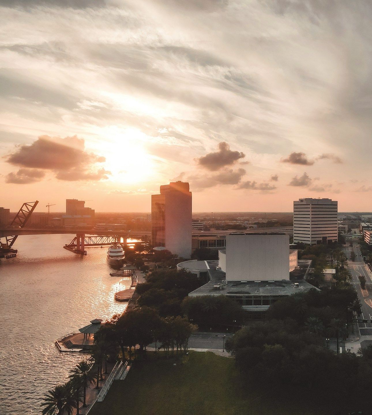 An aerial view of a city at sunset with a large body of water in the foreground