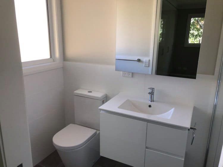 Bathroom With a Toilet , Sink and Mirror — Saurine Plumbing Services in Moss Vale, NSW