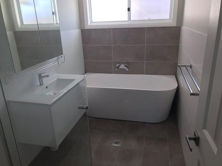 Bathroom With a Bathtub, Sink, Mirror and Window — Saurine Plumbing Services in Moss Vale, NSW