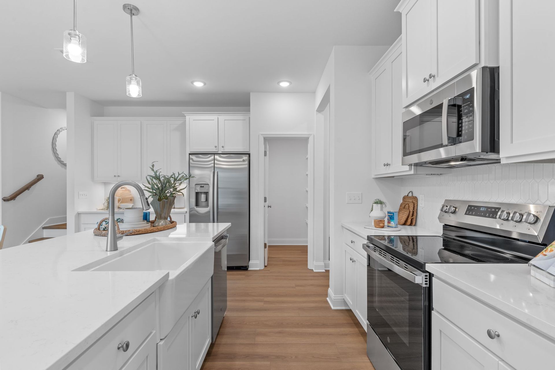 White kitchen with stainless steel appliances, island, and wood floor.
