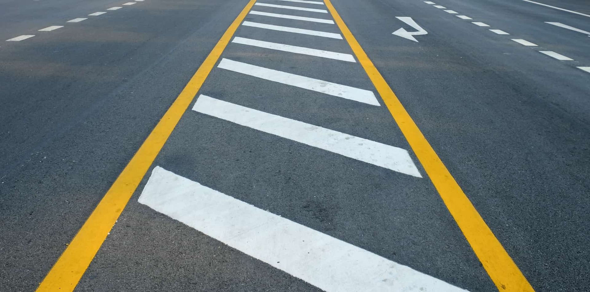 Roadway with yellow lines, a striped median, and a white directional arrow.