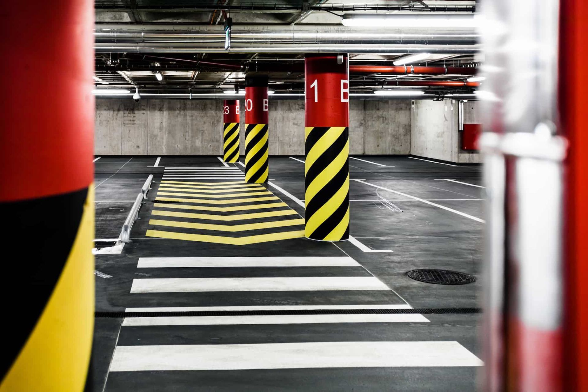 Parking garage interior with striped columns, crosswalk, and numbered signage.