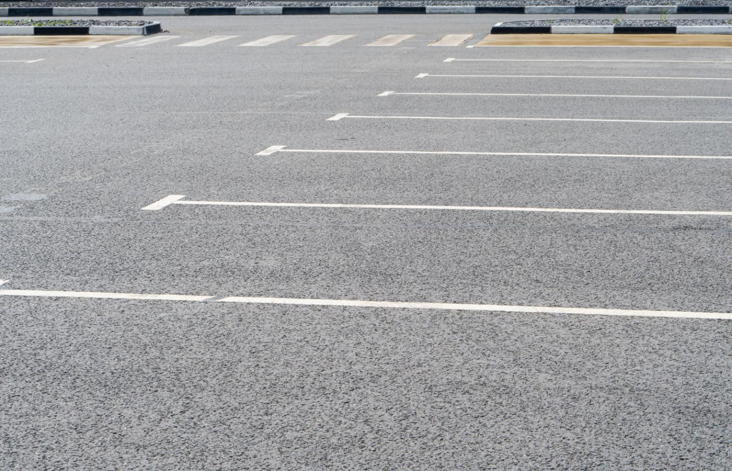 Empty asphalt parking lot with white parking lines.