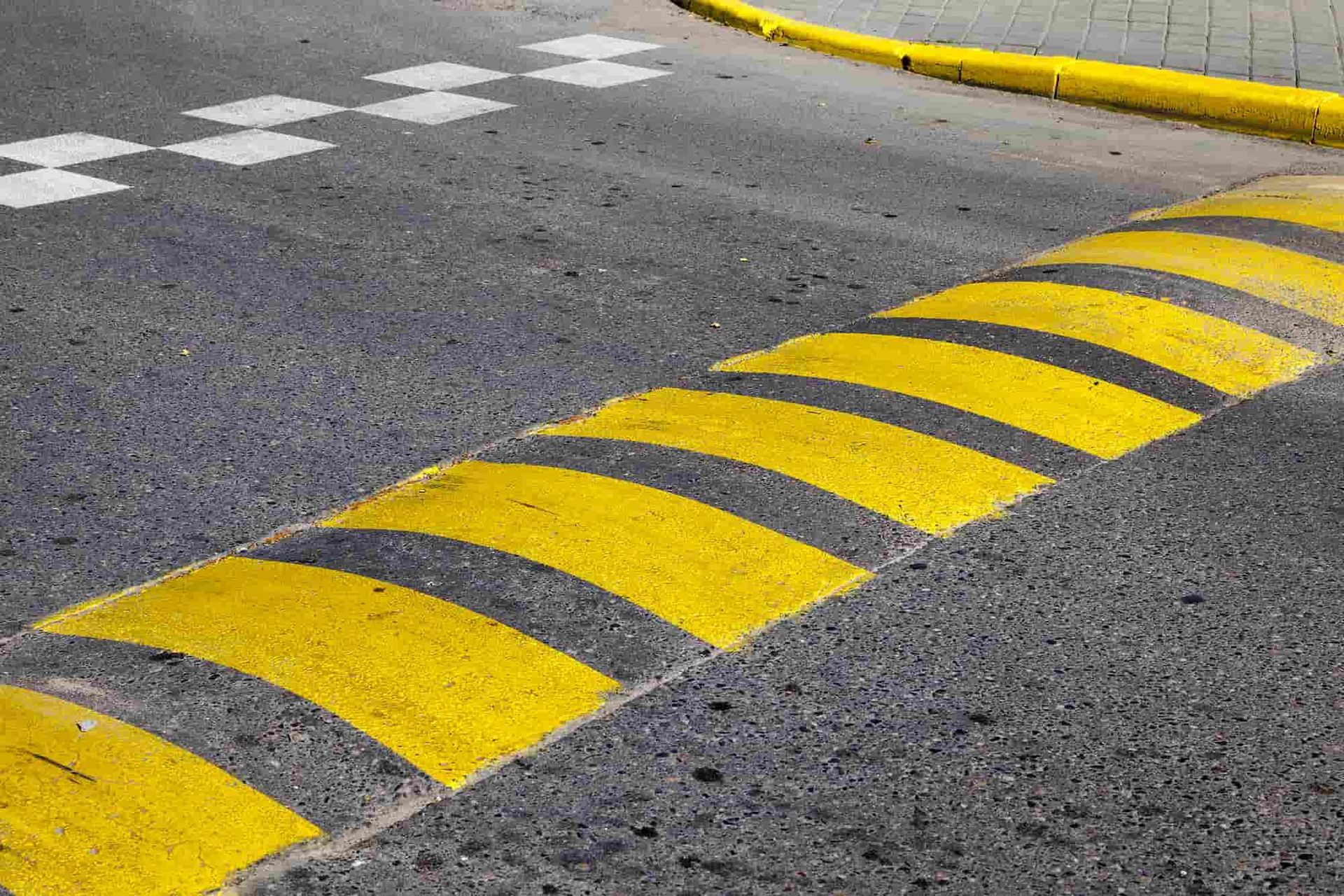 Yellow speed bump painted on asphalt road.