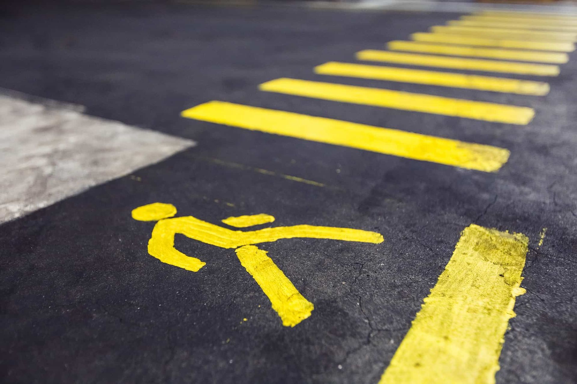 Yellow pedestrian crossing with person symbol painted on asphalt.