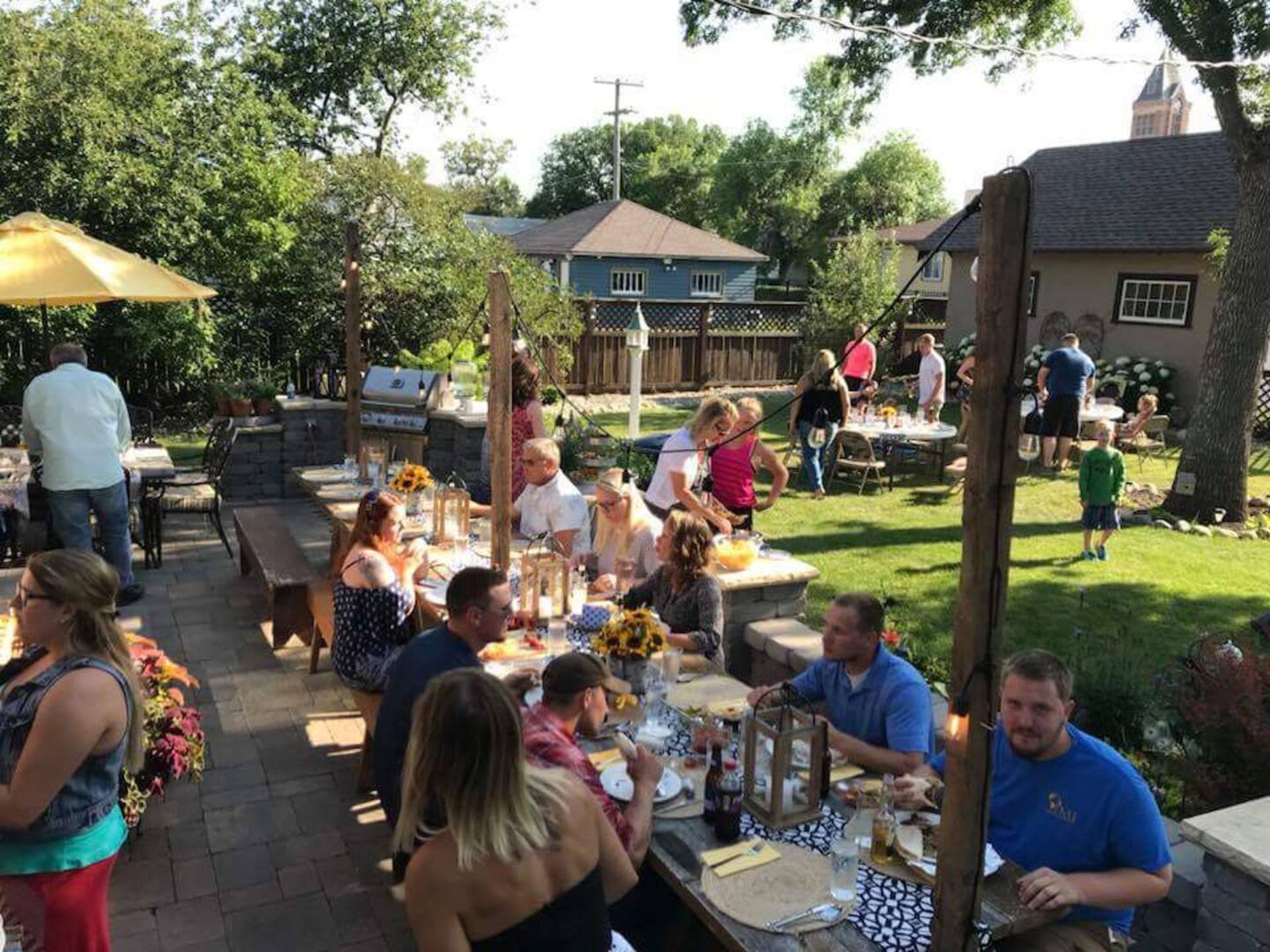 A group of people are sitting at tables in a backyard