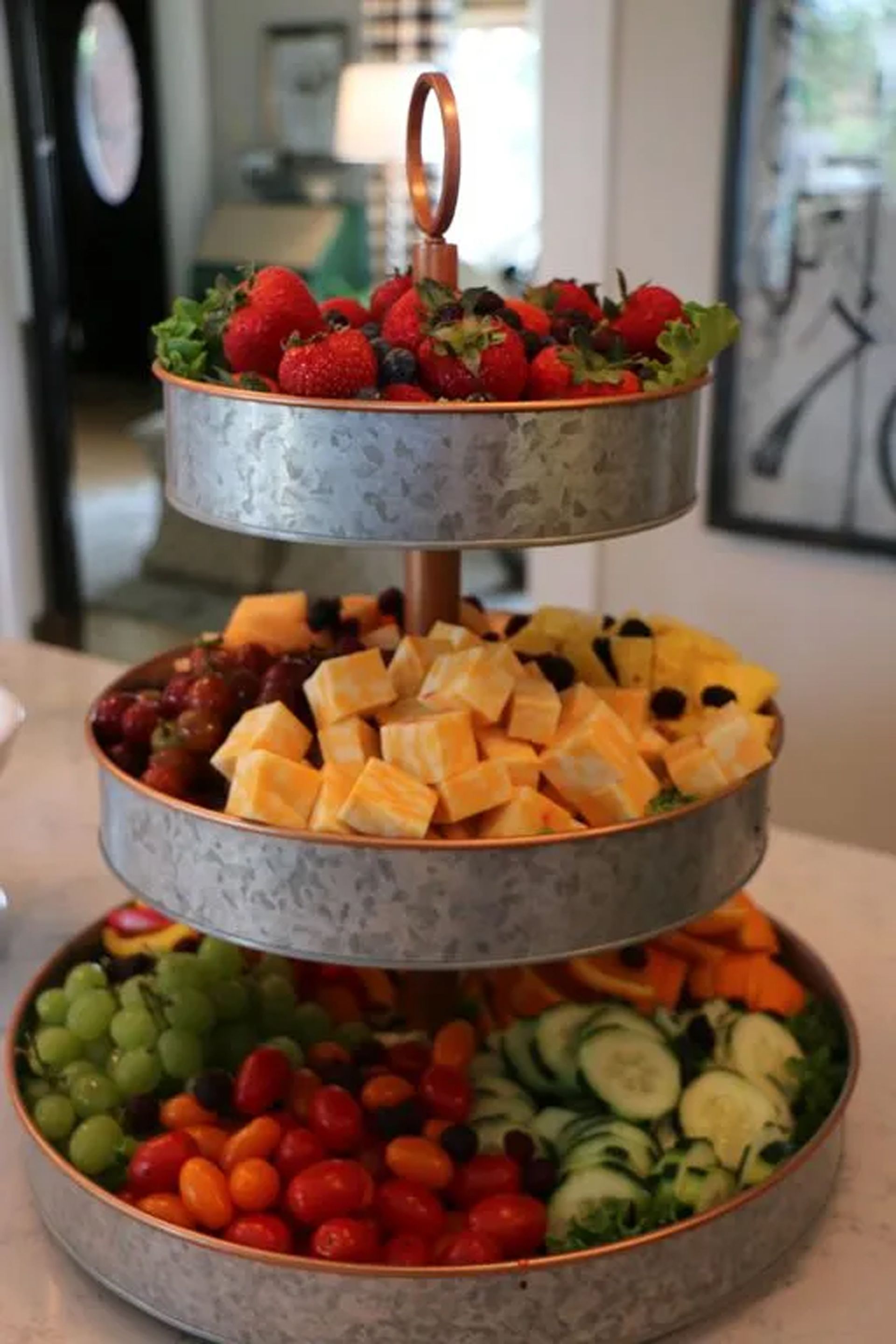 A three tiered tray filled with fruits and vegetables