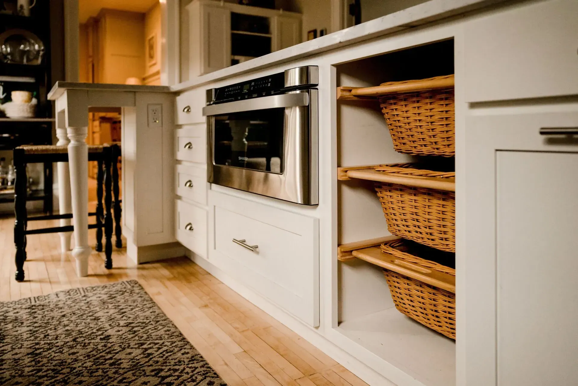 A kitchen with white cabinets and wicker baskets