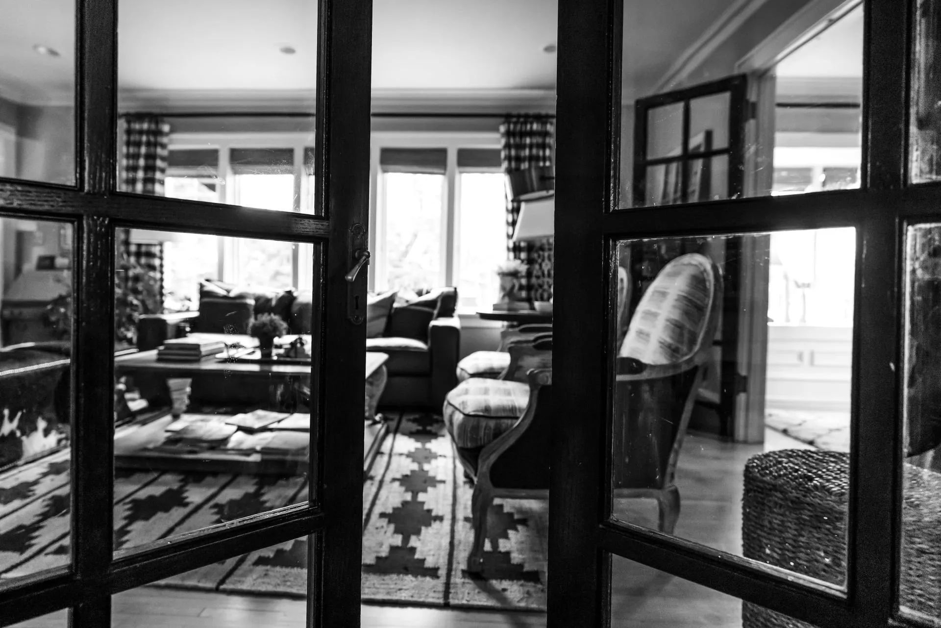 A black and white photo of a living room through a glass door.