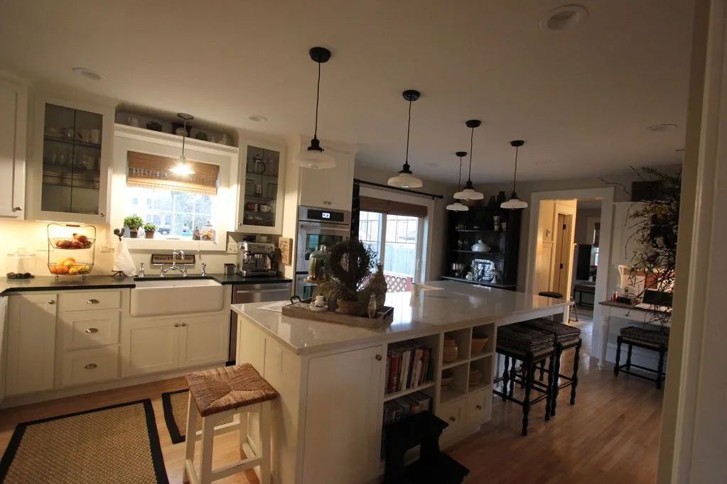 A kitchen with white cabinets and a large island in the middle
