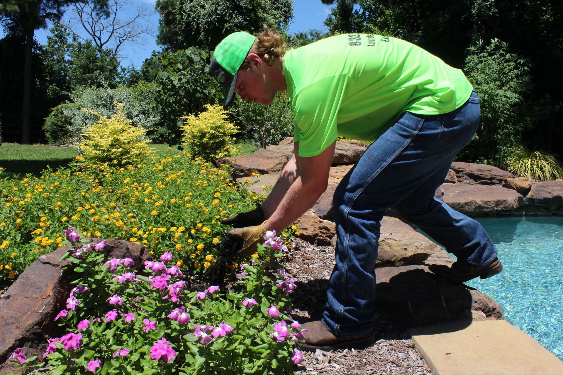 A man in a neon green shirt is working in a garden
