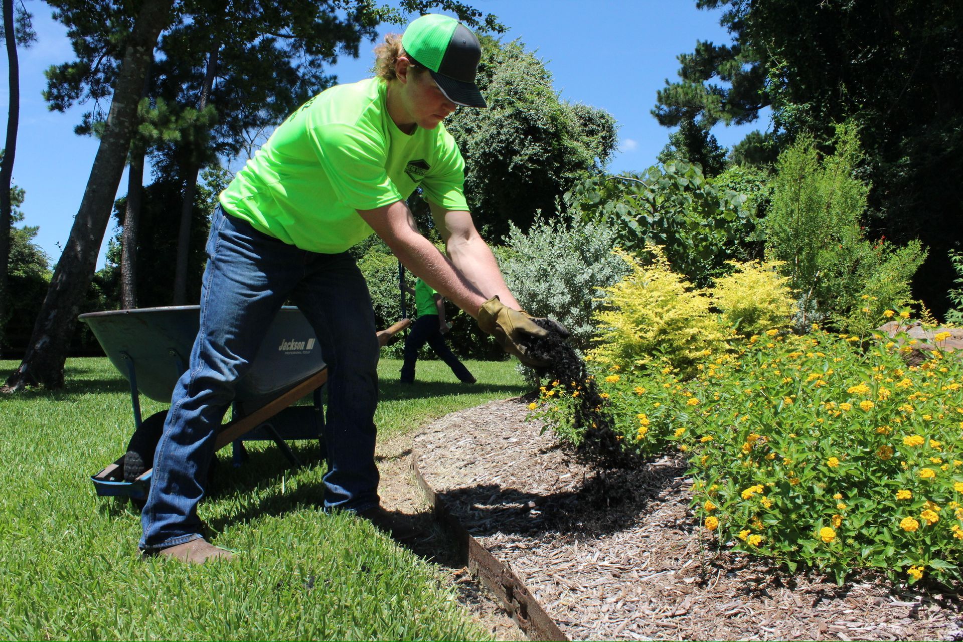 A man in a neon green shirt is working in a garden