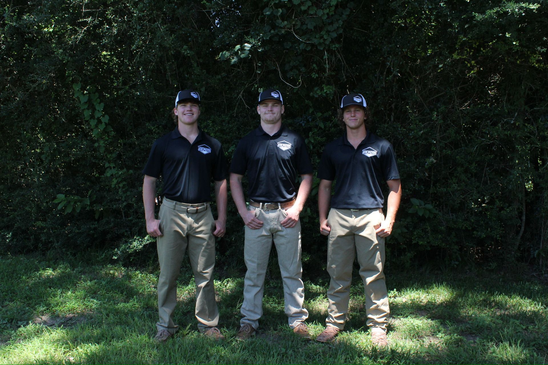Three men are posing for a picture in front of trees