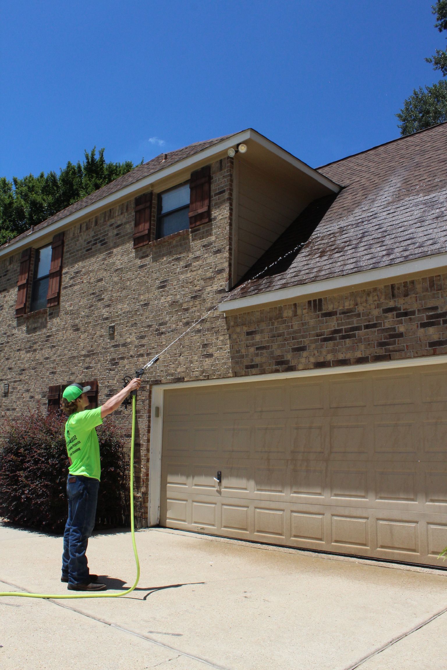 A man in a green shirt is measuring a garage door with a tape measure.
