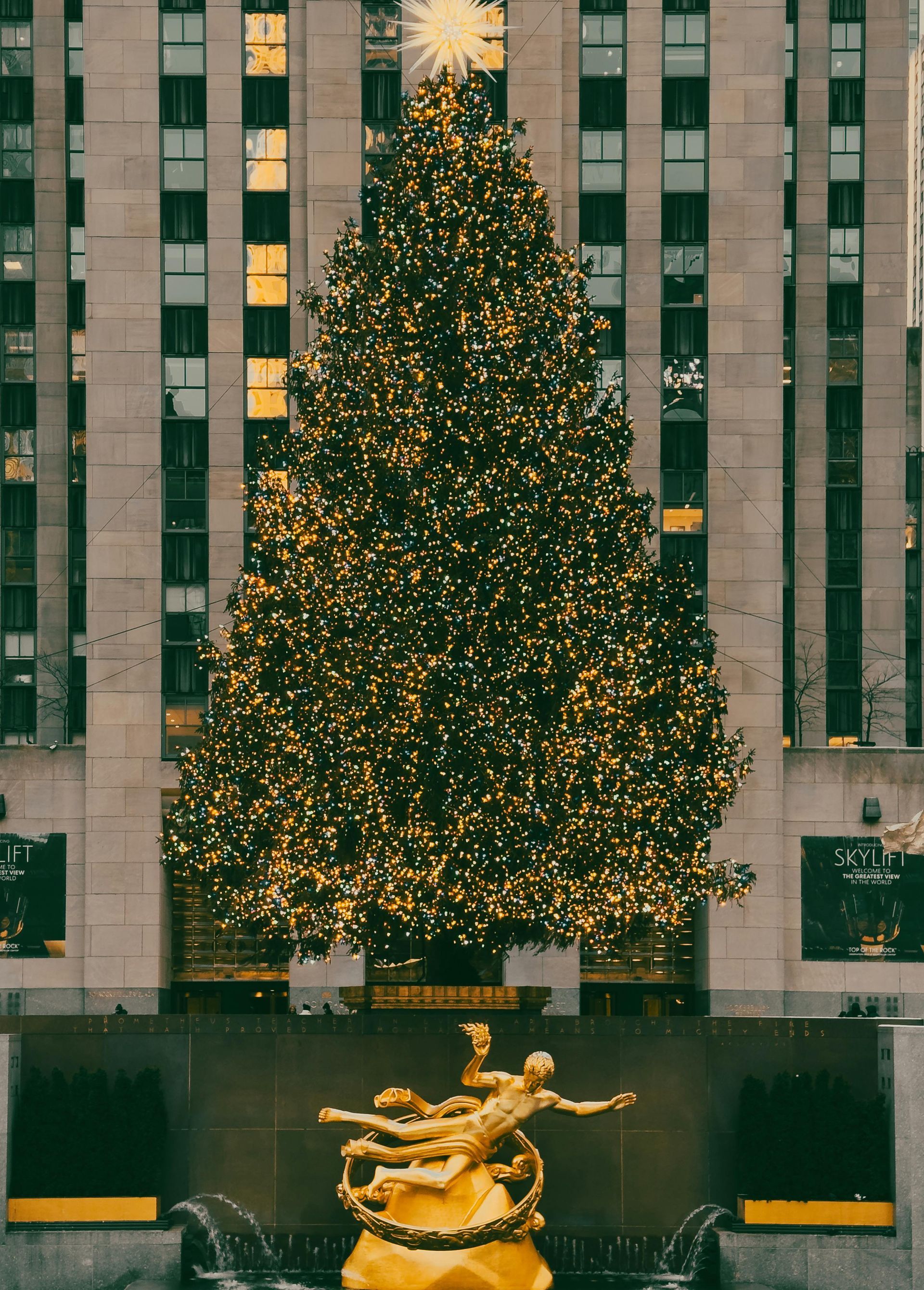 A large christmas tree with a statue in front of it