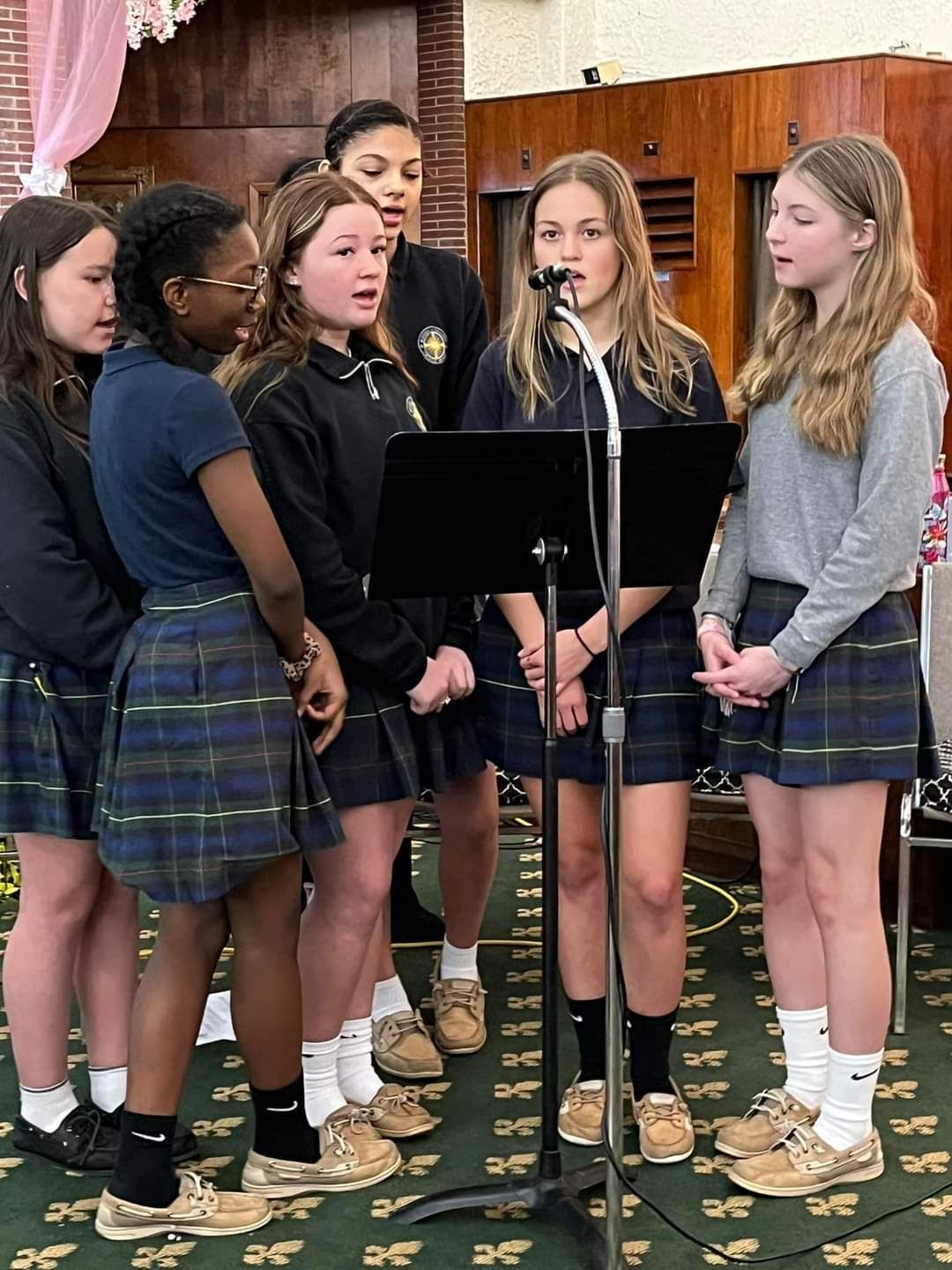 A group of young girls singing into a microphone