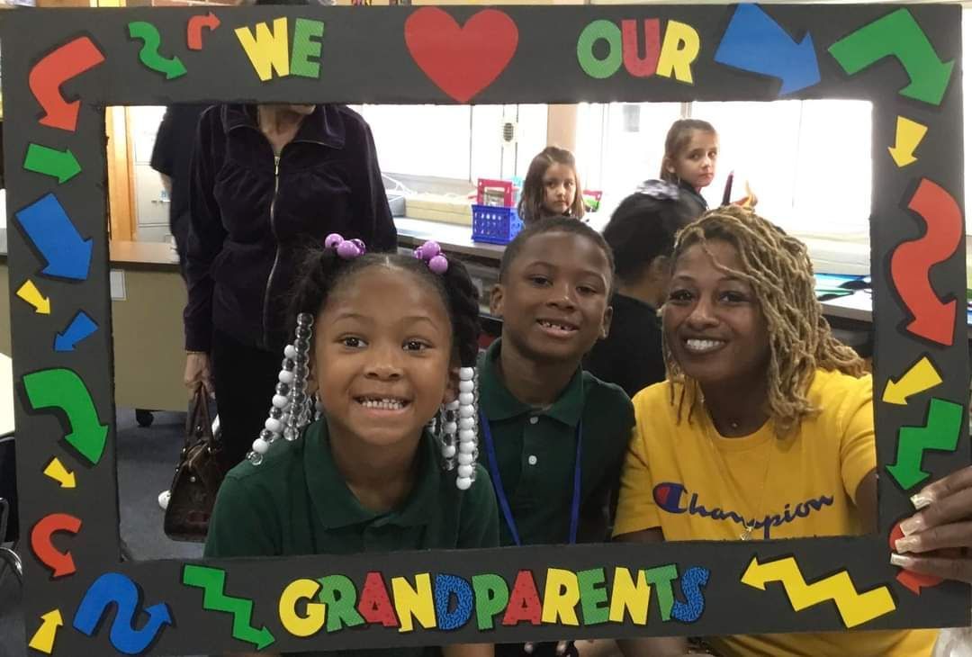 A group of children are posing for a picture with a frame that says grandparents