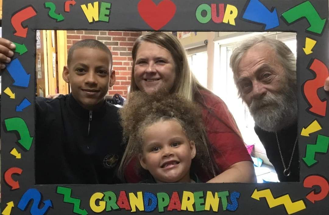 A family posing for a picture with a frame that says we love our grandparents