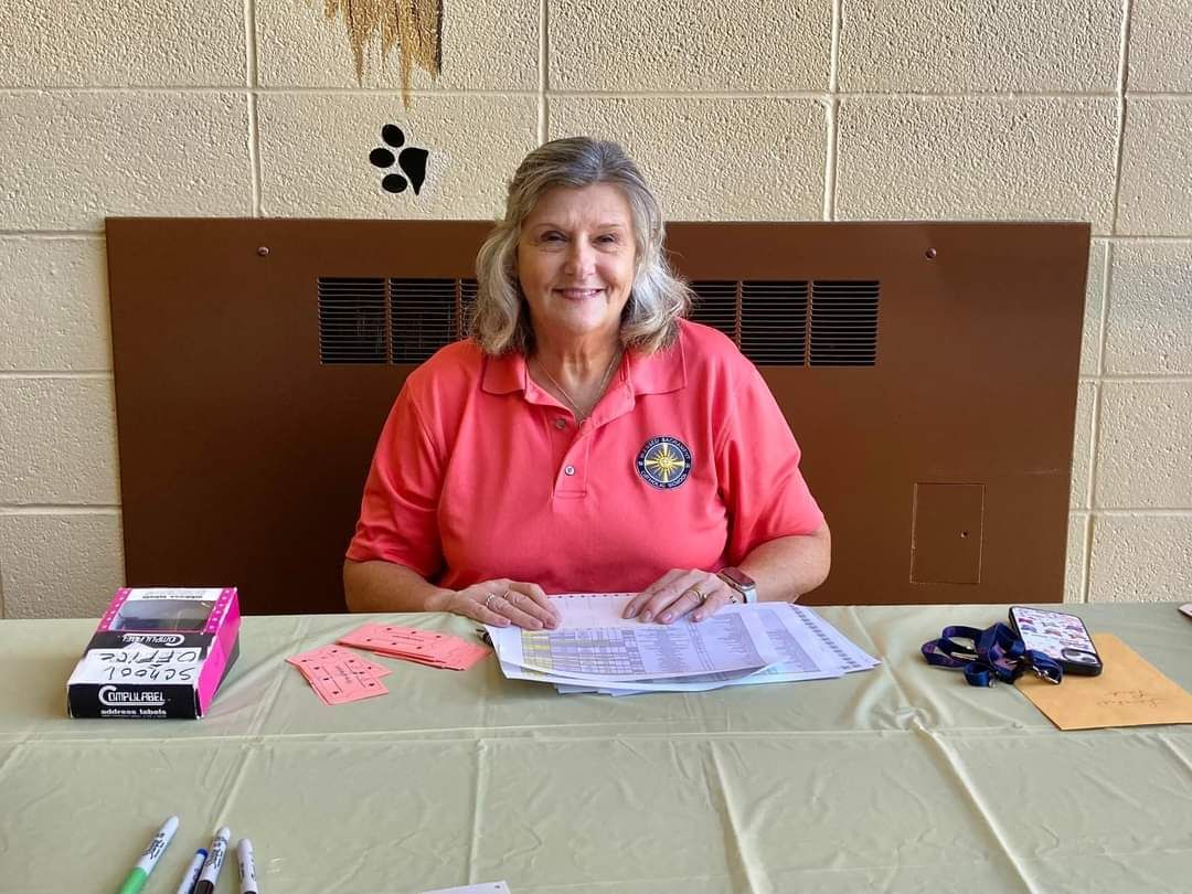 A woman in a pink shirt is sitting at a table