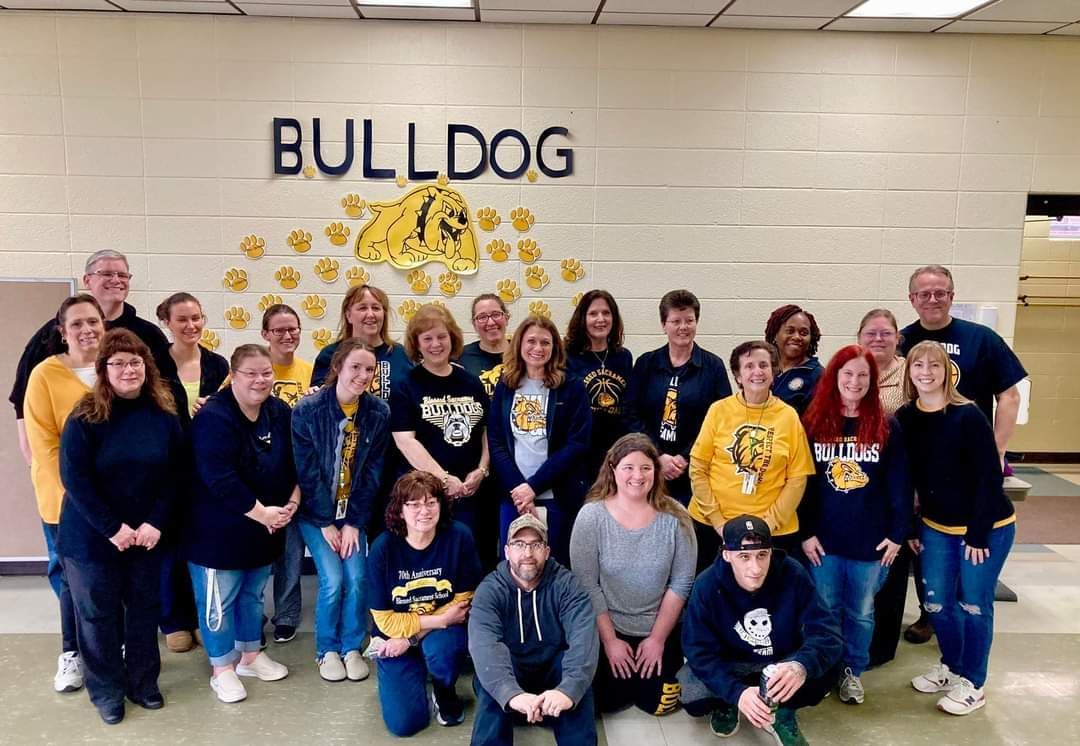 A group of people are posing for a picture in front of a wall that says bulldog