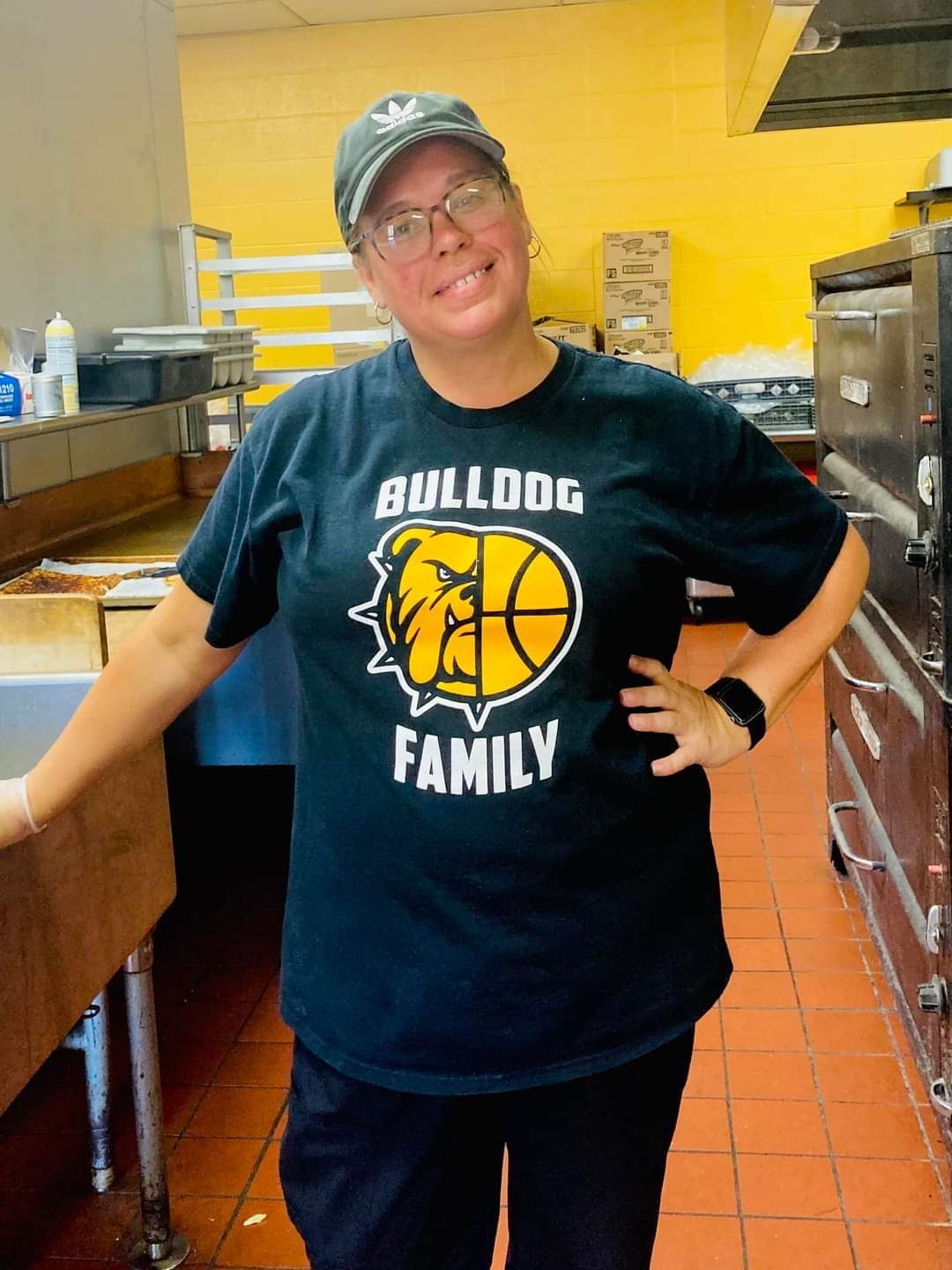 A woman in a green shirt is smiling in a kitchen