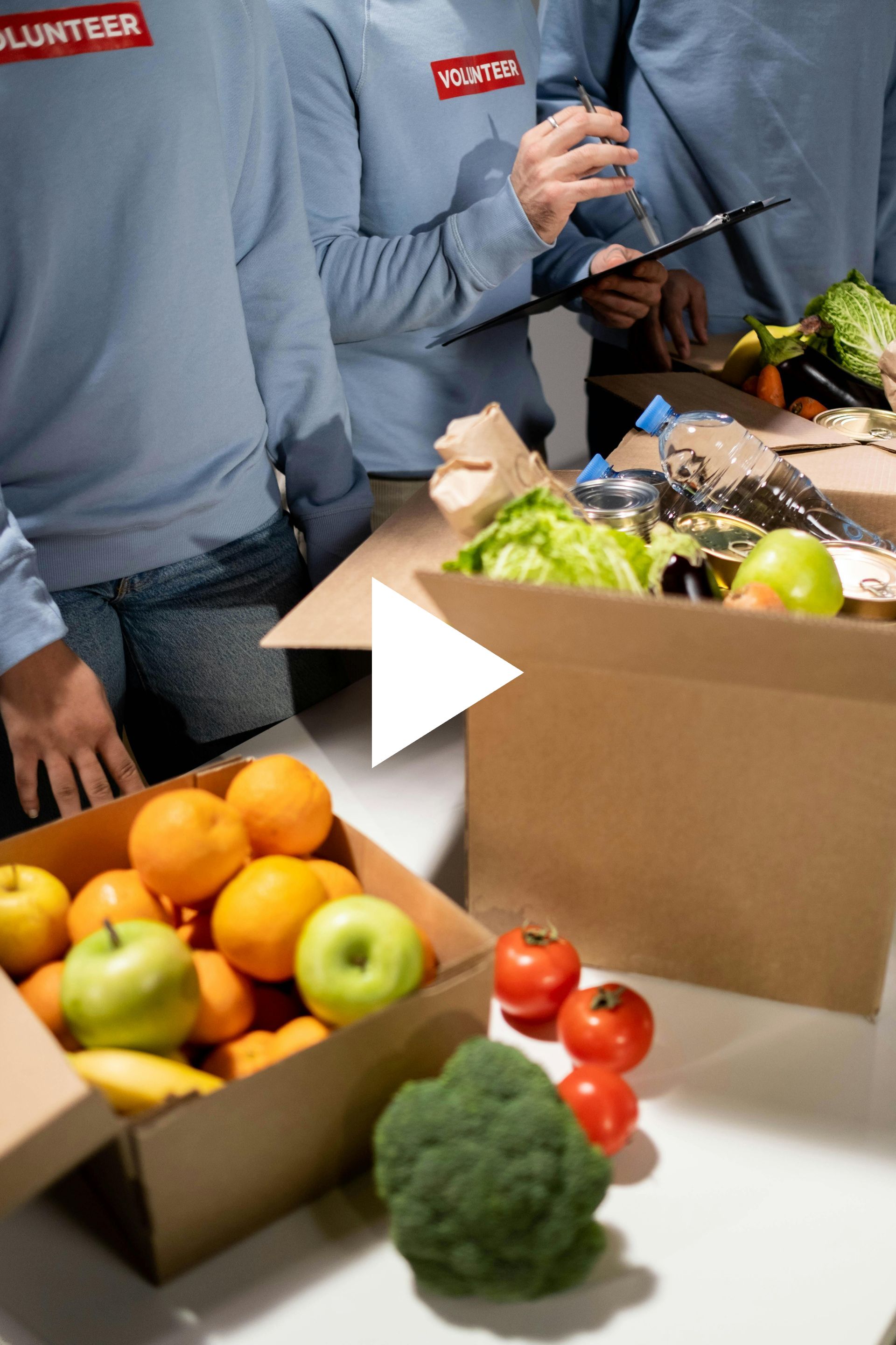 A group of volunteers are standing around a table with boxes of fruits and vegetables.