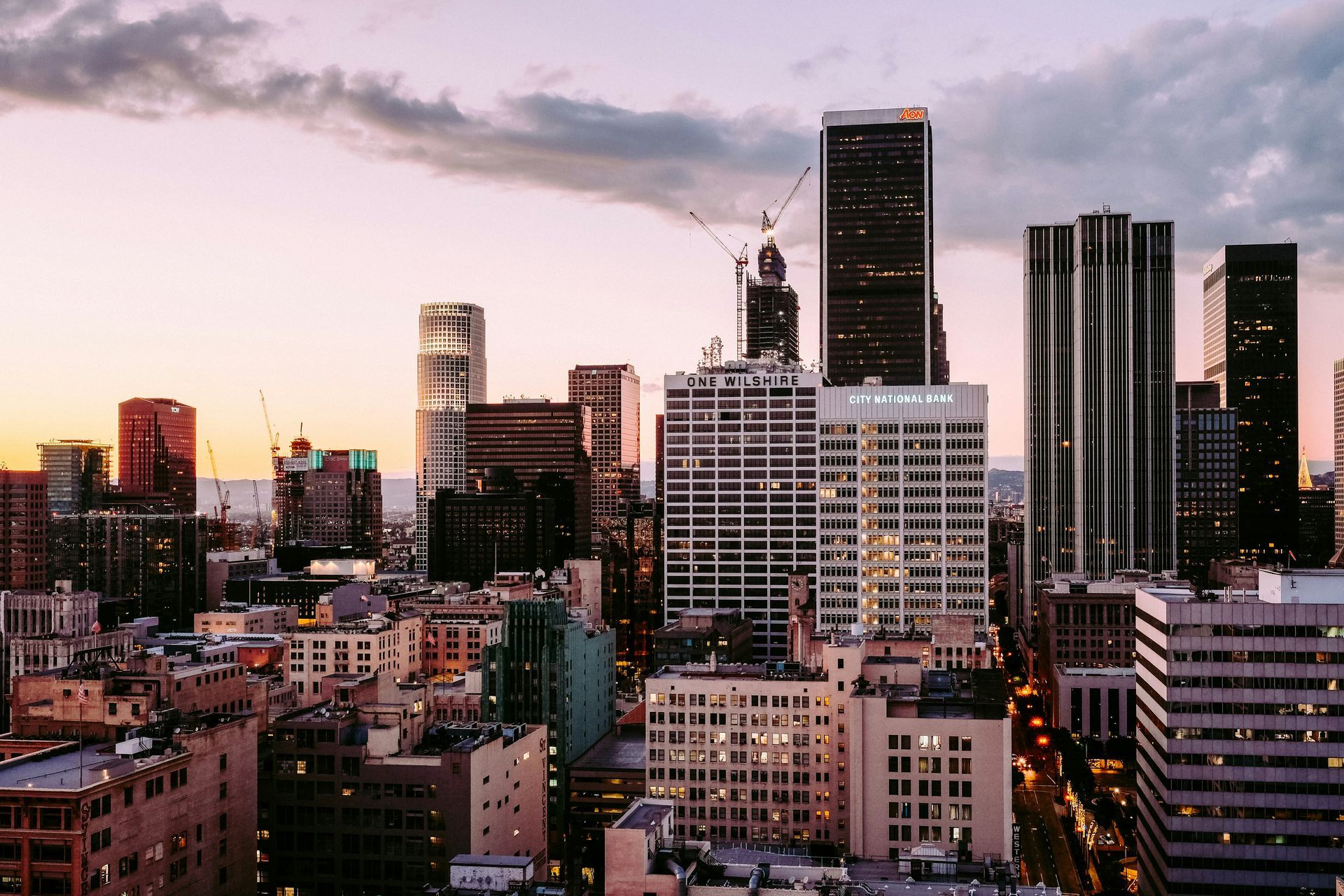City skyline at dusk with tall office towers and pink-purple sunset clouds
