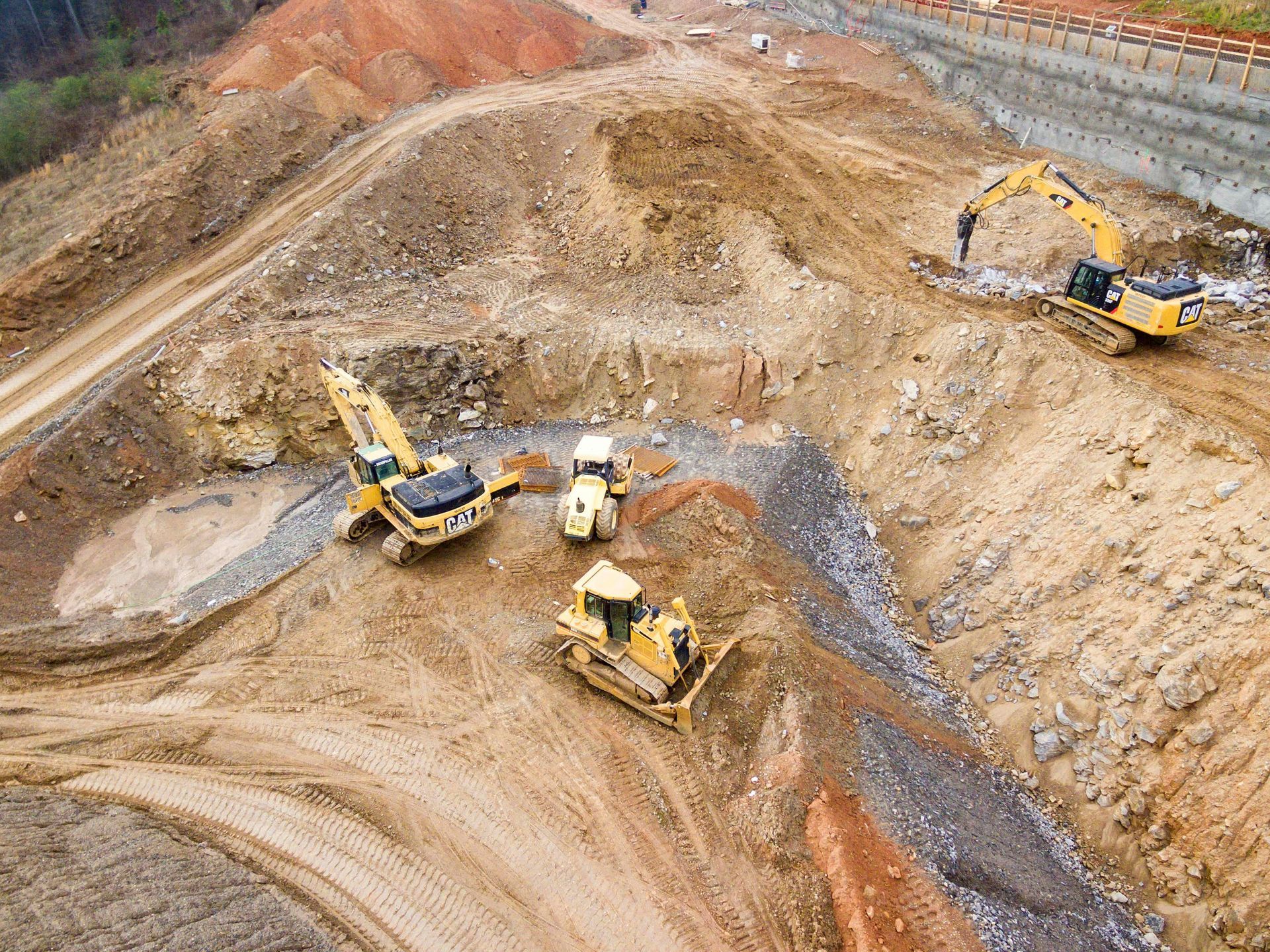 Earthmoving construction site with three excavators working on a terraced dirt excavation