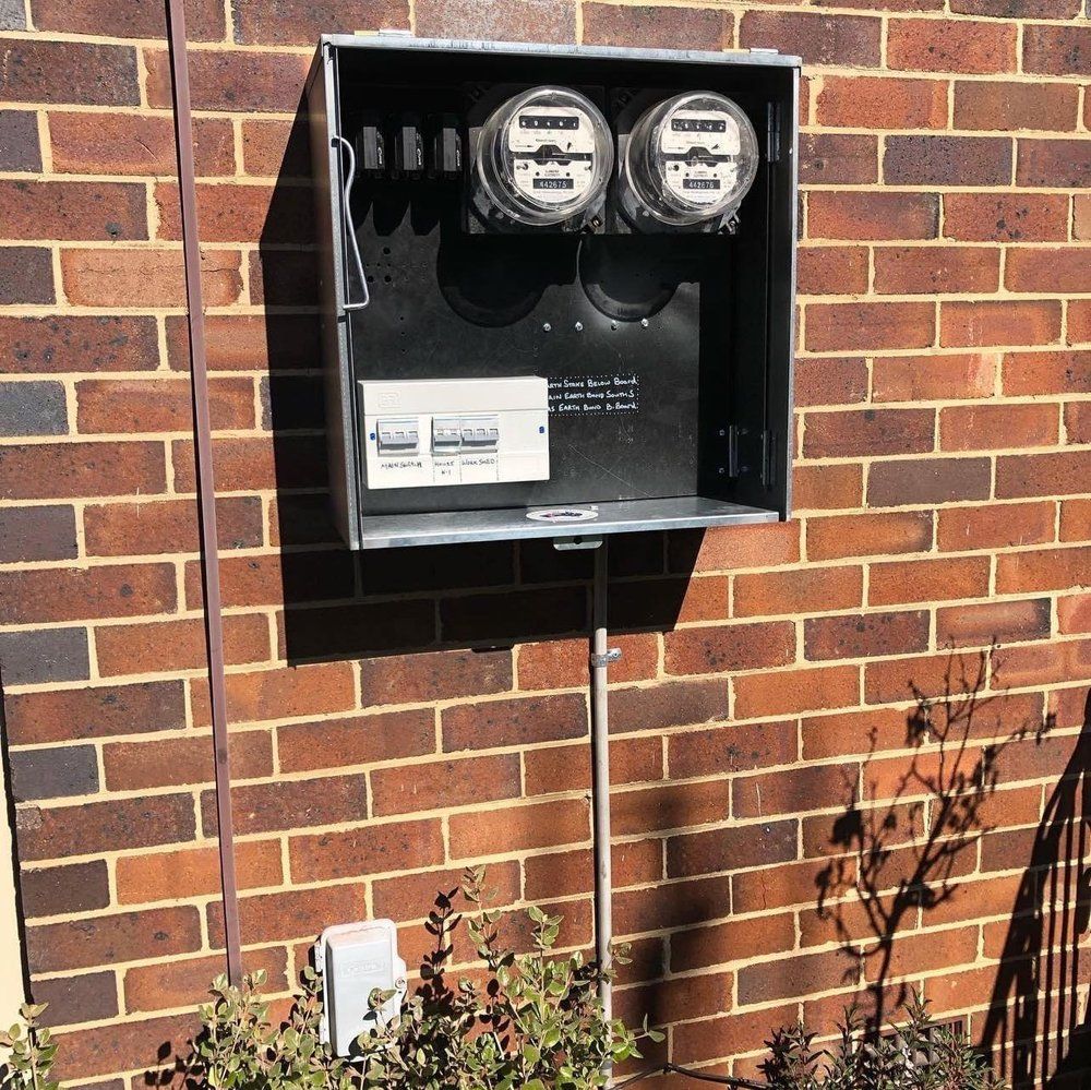 Man in hard hat drills into ceiling, standing on scaffolding in a construction site.