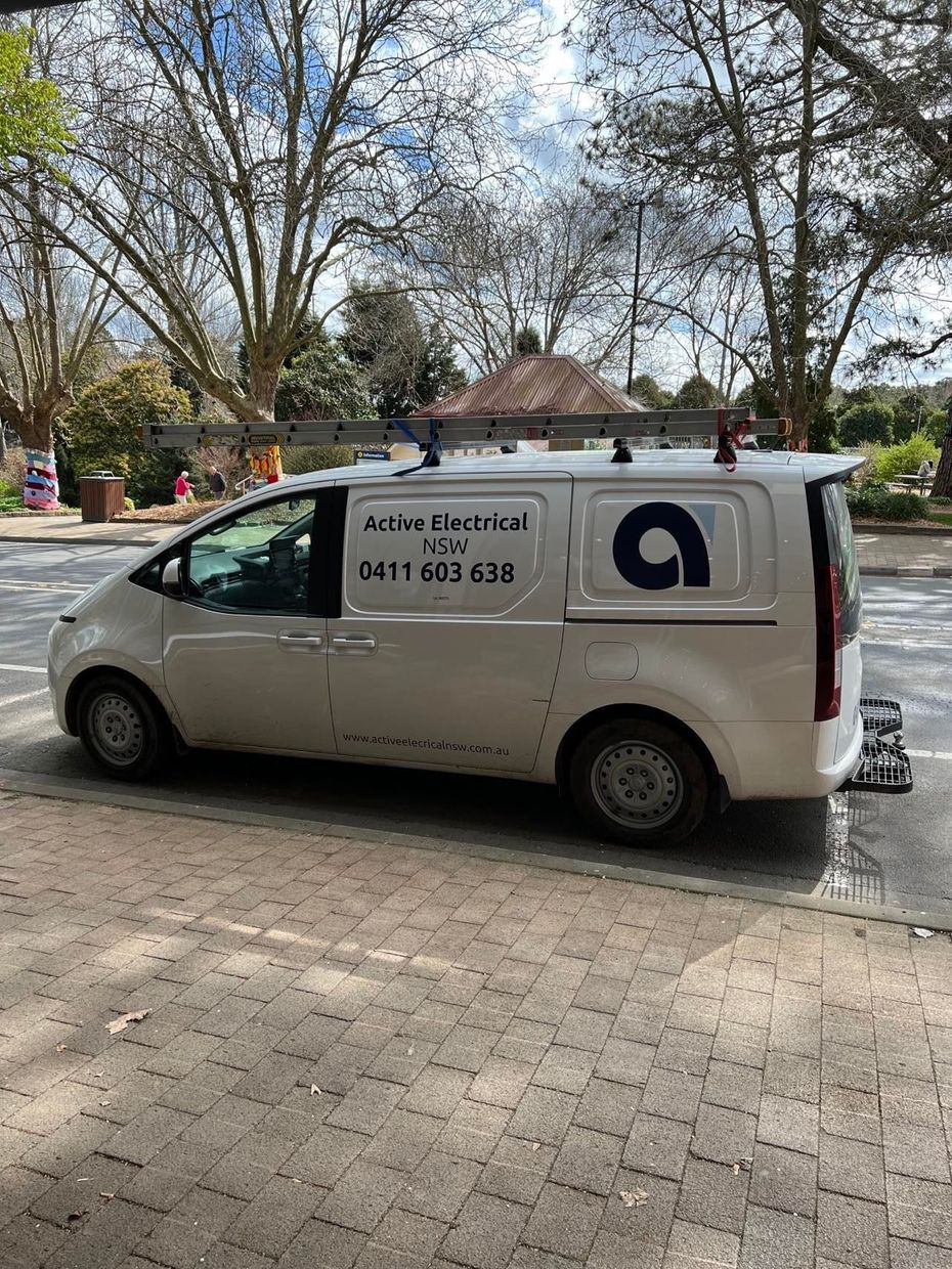Man wearing work gloves examines a door frame with a tool, outdoors, near a window.