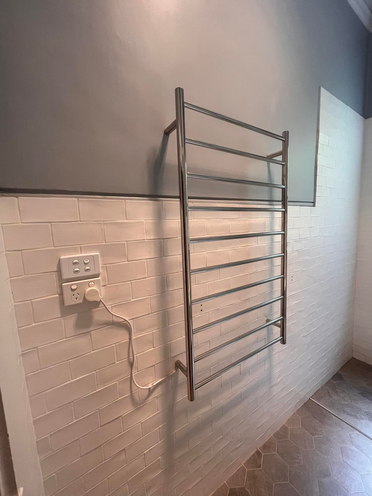 Man installing a light fixture on a white ceiling. He's holding a light bulb near a black track.
