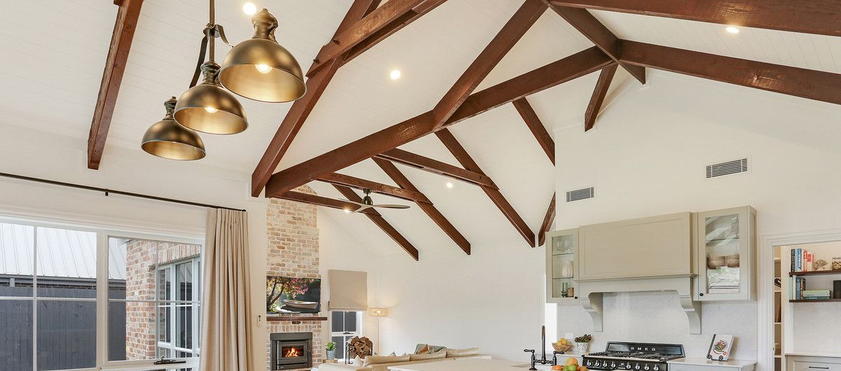 Person installing a smoke detector on a white ceiling with pendant lights.