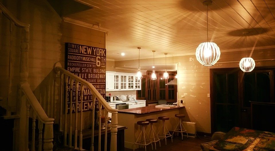 Warmly lit interior: staircase leads to kitchen with bar seating, pendant lights, and 