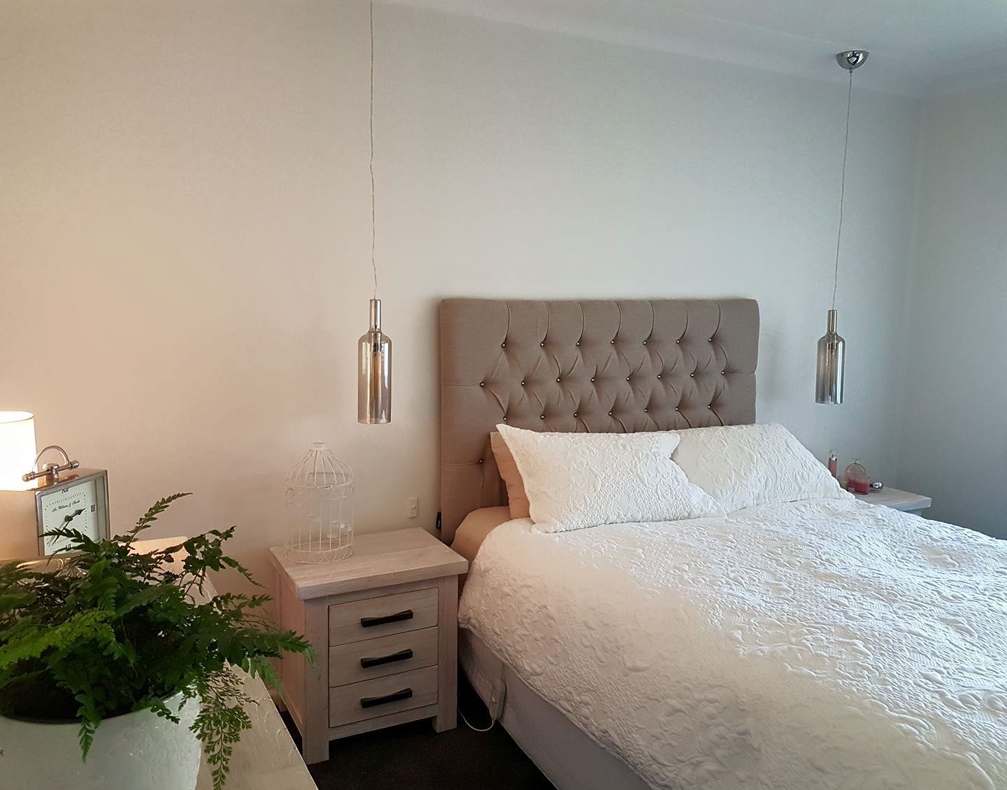 Bedroom with a bed, nightstands, pendant lights, and decorative plants.
