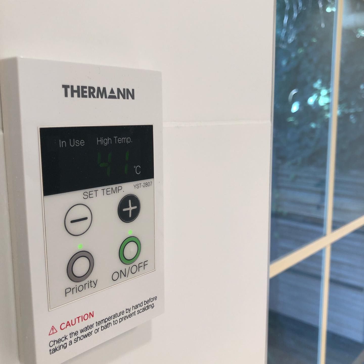 White Thermann water heater control panel with a display showing 