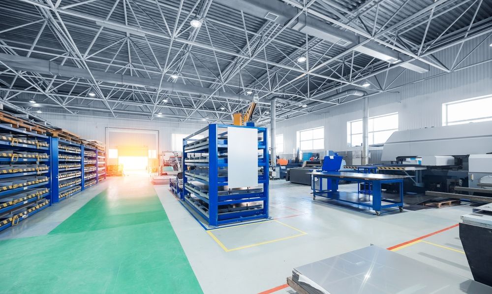 Warehouse interior with shelving, machinery, and bright lighting.