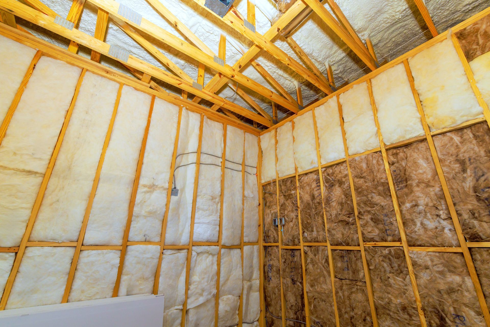 Interior of a building under construction, showing wooden frame, insulation, and roof rafters.
