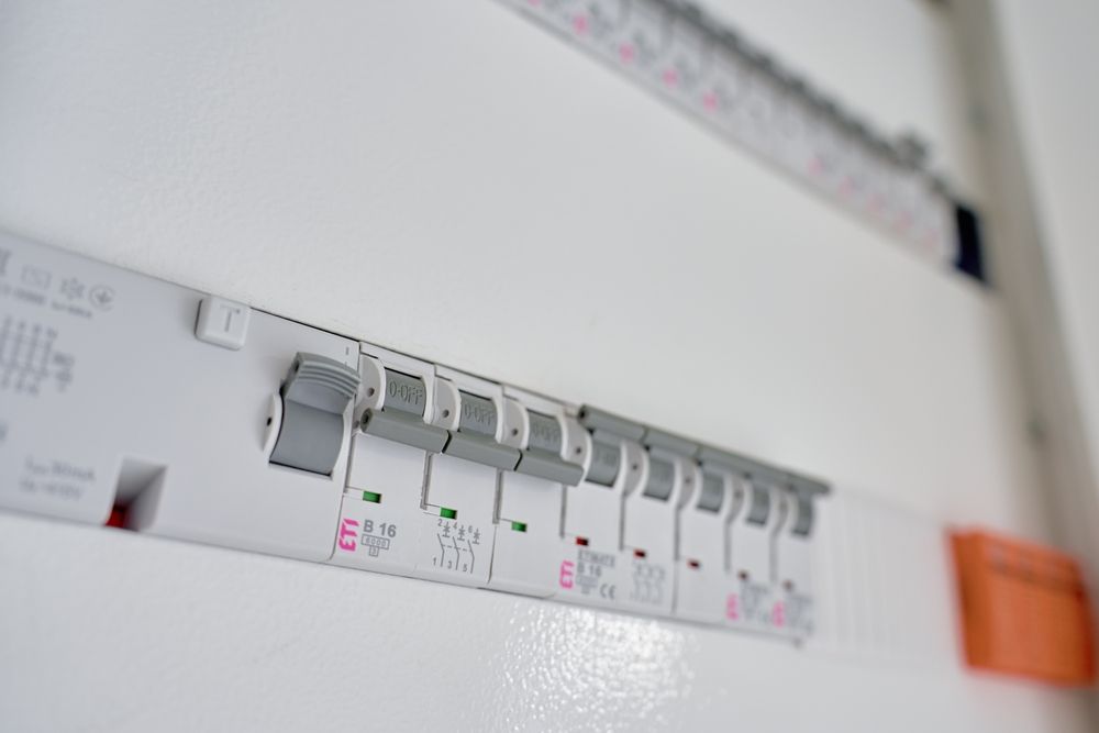 White electrical fuse box with several switches in the on position.