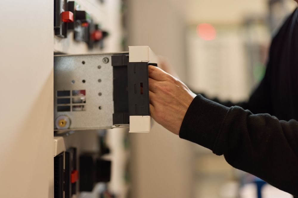 Person inserting a black and white electronic component into a panel.