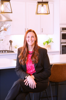 A woman is sitting on a bar stool in a kitchen.
