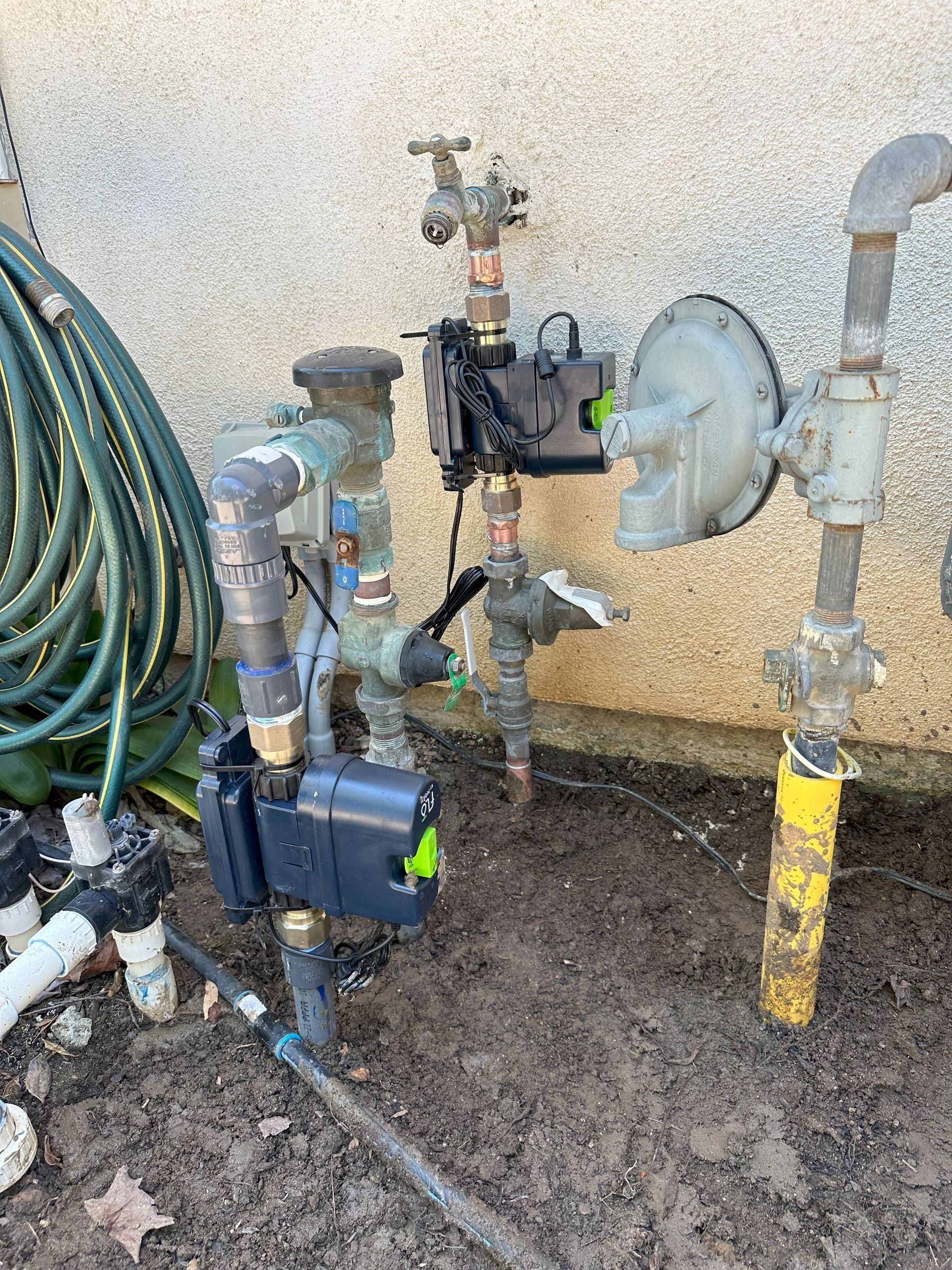 A bunch of pipes are sitting on the ground next to a wall.